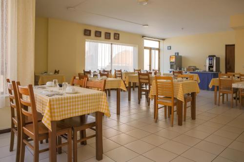 比索达雷加因佩里奥酒店的餐厅设有桌椅,配有黄色和白色的桌布