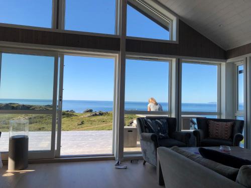 Gimsøy罗弗敦山林小屋的一间设有大窗户的房间,一位女士望向大海