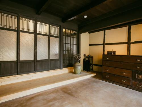 Tatsuno龍野城下町古民家ホテル kurasu的一间设有窗户、梳妆台和花瓶的房间