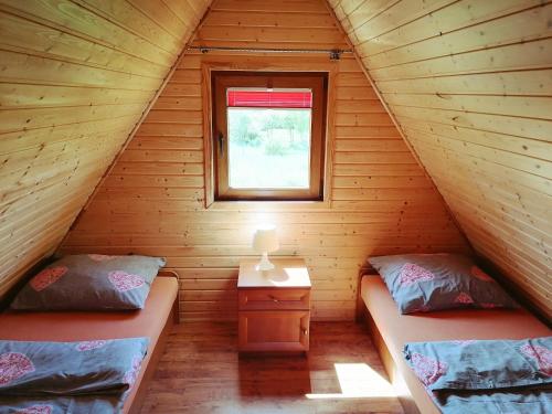 雅罗斯瓦维茨Domki Letniskowe - Leśne Zacisze的小木屋内的两张床,设有窗户