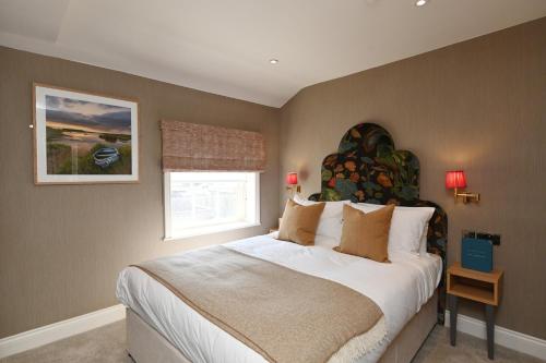 萨克斯曼德姆The Bell Hotel, Saxmundham的一间卧室设有一张大床和一个窗户。