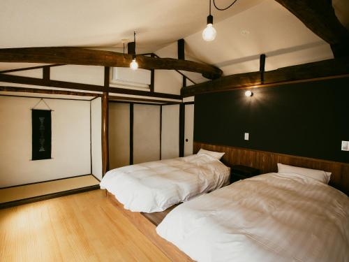 Tatsuno龍野城下町古民家ホテル kurasu的配有2张床的木地板客房