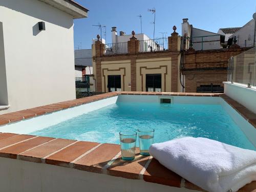 塞维利亚La Casa del Pintor Apartments的一座房子边缘的游泳池,两杯