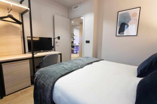 比亚雷亚尔Apartamento Milano Living Suites en Vila real的一间卧室配有一张床、一张书桌和一台电视