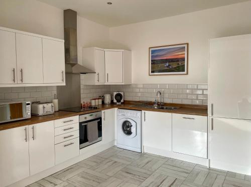 莱瑟姆-圣安妮Apartment 33 Lytham的厨房配有白色橱柜和洗碗机。
