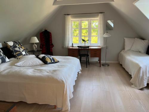 约灵Fuglsang Bed & Breakfast的一间卧室设有两张床、一张桌子和一个窗口。