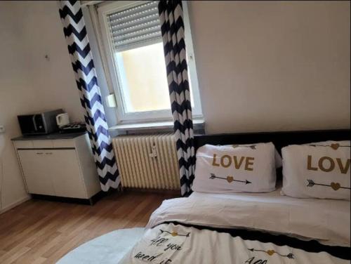 达姆施塔特Wohnung im Zentrum von Darmstadt的一间卧室配有一张带爱情枕头的床和窗户。