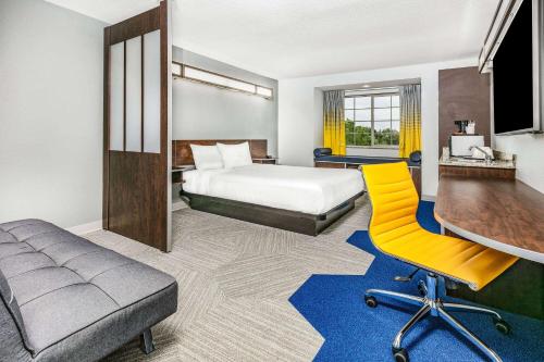 奥斯汀麦克罗迪尔温德姆韦汉姆奥斯丁机场酒店的酒店客房,配有床和黄色椅子
