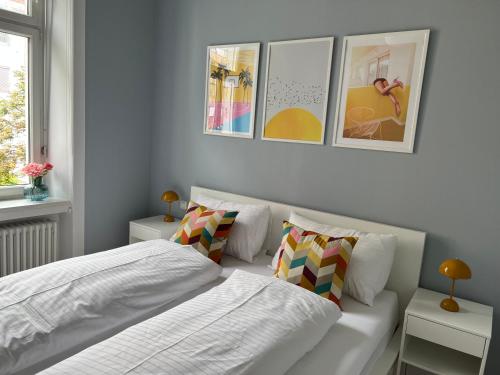 克拉根福Das Domizil的一间卧室设有两张床,墙上挂着一些图片