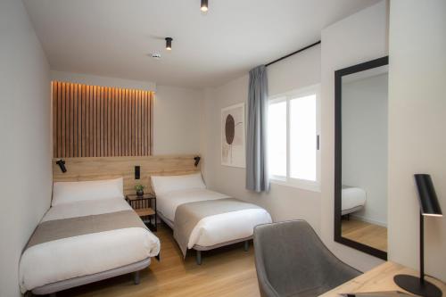 布尔哈索特Aila II Hotel Boutique by SingularStays - Digital Access的一间设有两张床、椅子和镜子的房间