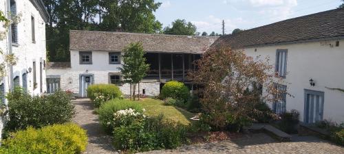 舍兰La ferme de la Chapelle - Gîte et chambres d'hôtes的一座古老的白色房子,前面有一个花园