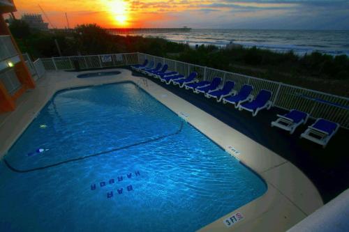默特尔比奇巴港酒店的一个带椅子的游泳池,日落时分享有海景