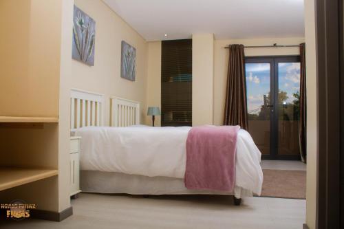 哈博罗内Staybridge Golfview Suites的一间卧室配有一张带白色床单的床和一扇窗户。