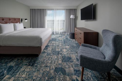 坦帕坦帕机场西岸福朋喜来登酒店的酒店客房配有一张床、一把椅子和一台电视。