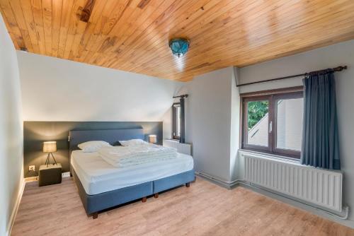 WingeneFantastische vakantiewoning aan het bos的一间卧室设有一张床和木制天花板