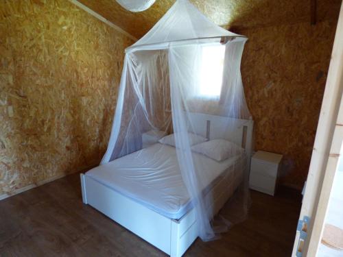 Bouillé-CourdaultLe Carbet Vendéen的客房内的白色床和天蓬