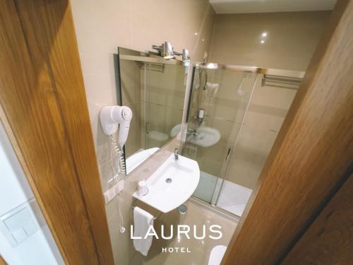 劳林哈Laurus Hotel的一间带水槽和玻璃淋浴的浴室