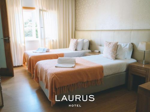 劳林哈Laurus Hotel的酒店客房带两张带橙色床单的床