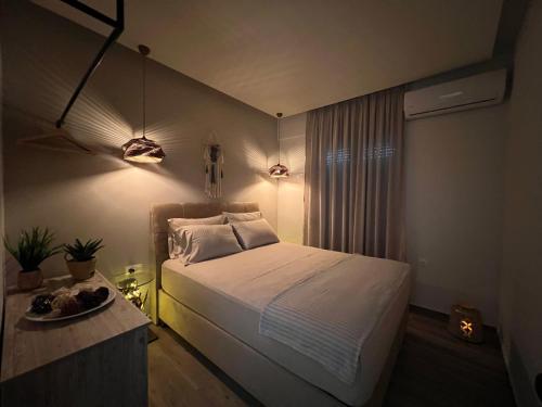 亚历山德鲁波利斯Supreme Malibu Suite的一间卧室配有一张床、一张桌子和灯