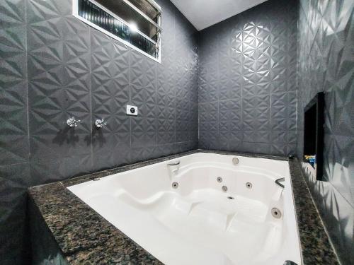南圣卡埃塔诺Calamares Hotel São Caetano的浴室设有白色浴缸,拥有灰色的墙壁。