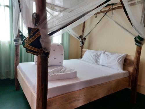 莫希Hill View Garden Hotel的卧室配有带白色床单和枕头的天蓬床。