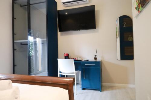 萨萨里Hermitage Suites的一间卧室配有蓝色的书桌和墙上的电视。