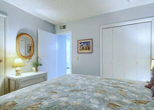格尔夫海岸Gulf Shores Plantation Condos的一间卧室配有一张大床和镜子