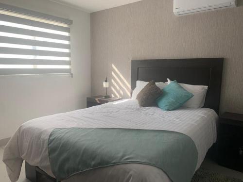 瓜达鲁佩镇San Miguel Cabañas的一间卧室配有一张带蓝色枕头的大床