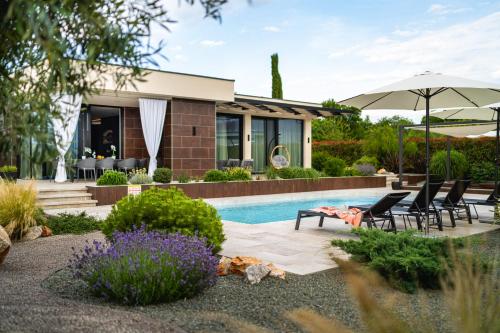 克尔克Villa Blumarine的一座带游泳池、椅子和遮阳伞的房子