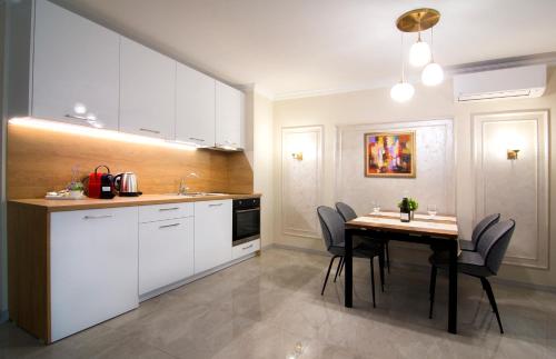 普罗夫迪夫Odrys Apartments的厨房配有白色橱柜和桌椅