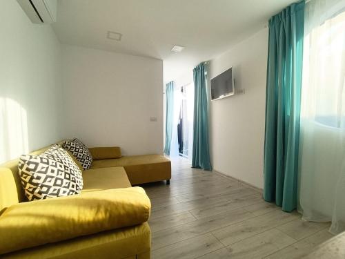 北马马亚-讷沃达里Tiny Village Mamaia Nord - House 2的客厅配有黄色沙发和蓝色窗帘