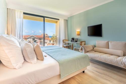 莫尼兹港Studios by Aqua Natura Hotels的一间卧室配有一张大床和一张沙发