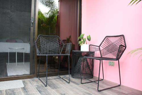 乌维塔Hotel Daleese的两把椅子和一张桌子,旁边是粉红色的墙壁