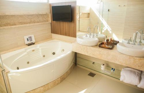 圣玛丽亚伊泰姆比宫酒店的浴室设有2个水槽、浴缸和镜子
