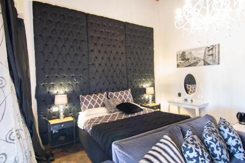 卡塔尼亚La Corte Della Regina的一间卧室配有大型黑色床头板和一张床
