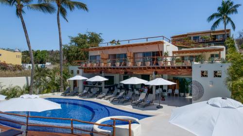 布塞里亚斯Hotel Ysuri Bucerias的一个带椅子和遮阳伞的游泳池的度假酒店