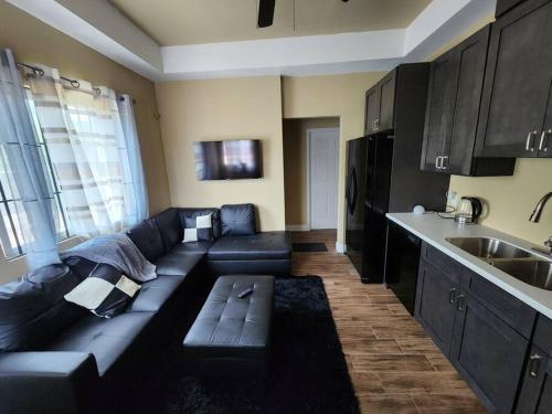普罗维登西亚莱斯岛StoneSide Villa的一间带黑色沙发的客厅和一间厨房