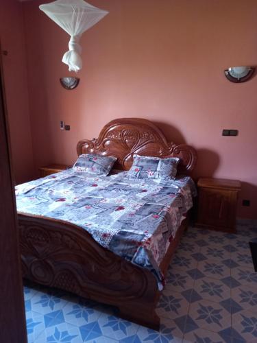 济金绍尔Villa meublée climatisée的一间卧室配有一张木床,床上有被子