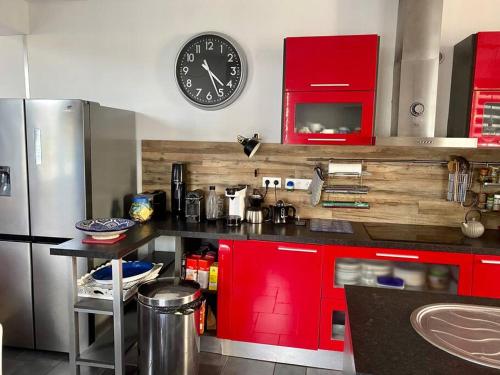 卡布尔kerwatt的一间厨房,里面装有红色橱柜,墙上挂着一个时钟