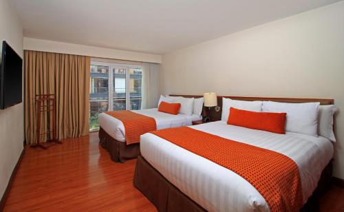 波哥大Hotel Windsor House Inn By GEH Suites的酒店客房设有两张床和窗户。