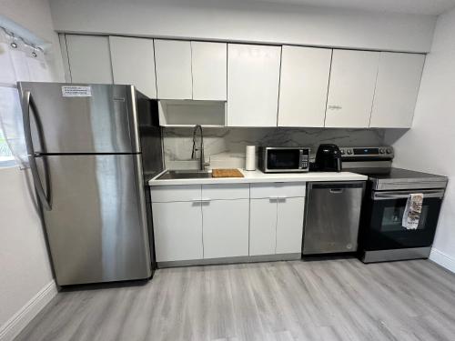 迈阿密World Connect Miami的厨房配有白色橱柜和不锈钢冰箱