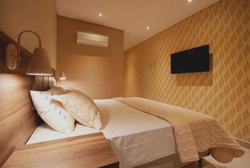 瓜鲁柳斯Guess Hotel & Motel的卧室配有一张床,墙上配有电视。