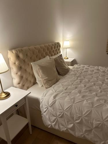 什切齐内克Premium Apartament Polna Szczecinek的一间卧室配有一张大床、两张桌子和两盏灯。