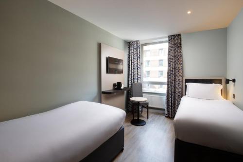 伦敦Royal National Hotel的酒店客房设有两张床和窗户。