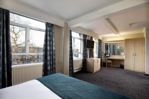 伦敦Bedford Hotel的酒店客房设有一张床、一张书桌和窗户。