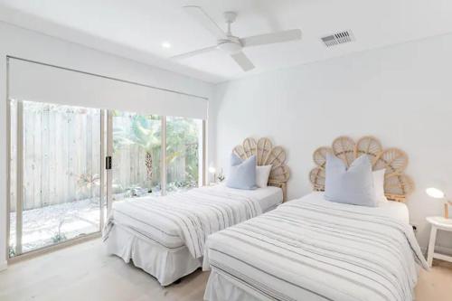 努萨角Poinciana House—Luxury Noosa Retreat close to Beach的白色客房的两张床,设有窗户