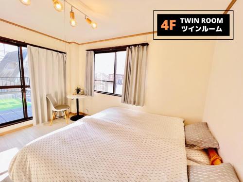 大阪Jen's House Osaka的卧室配有床、桌子和窗户。