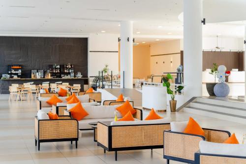 珍南海滩Wings by Croske Resort Langkawi的大堂设有橙色和白色的椅子和桌子。