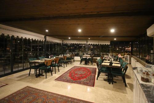 格雷梅卡帕多西亚洛克酒店的一间带桌椅的餐厅和一间大窗户的大房间