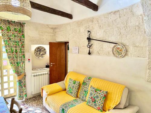 马丁纳弗兰卡Trulli Fenice的客厅设有黄色沙发和石墙